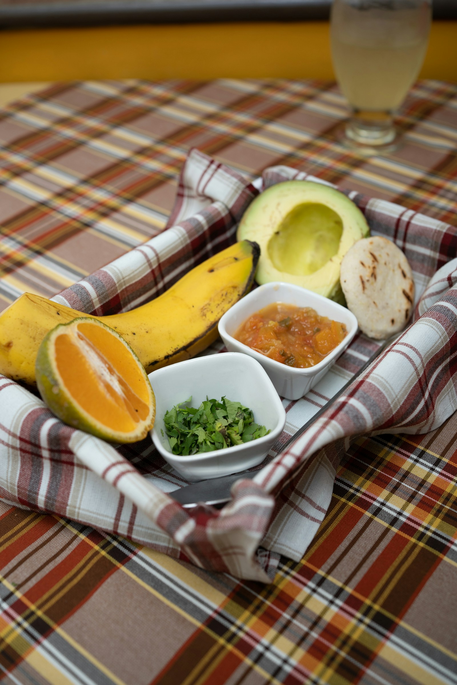 Plateau d'ingrédients latino-américains : plantain, avocat, arepa, orange, salsa et coriandre